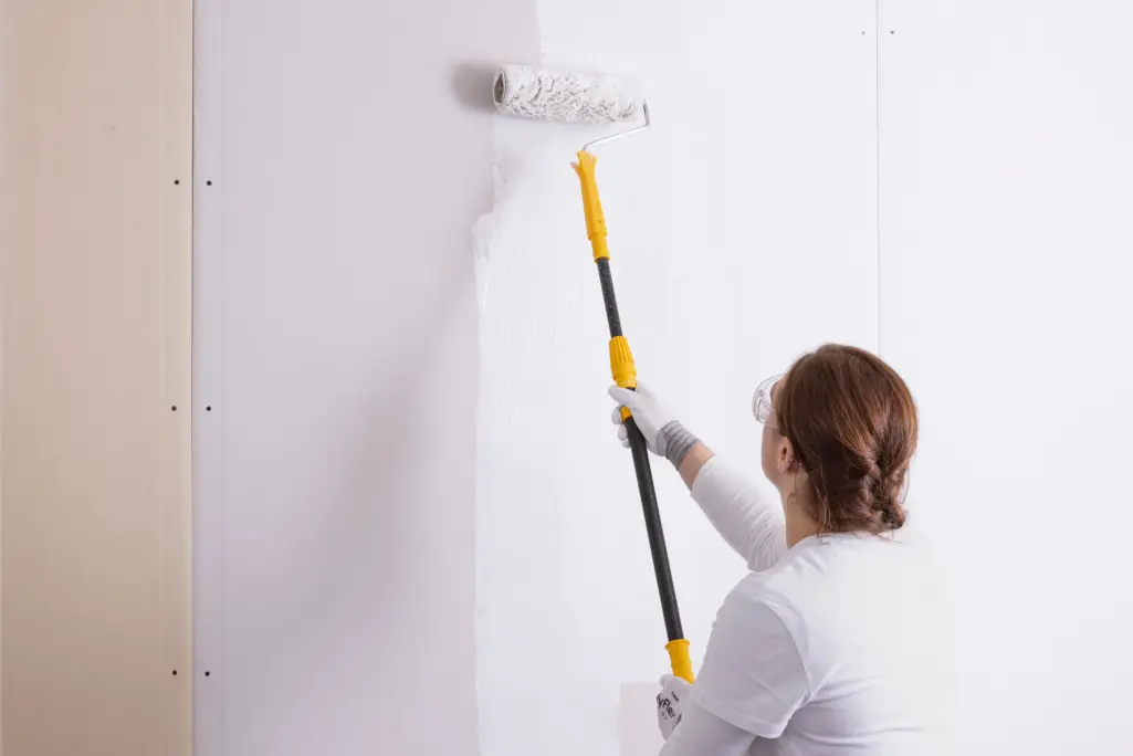 Frau streicht mit Farbrolle