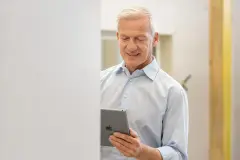 Ein Mann mit iPad steht vor einer Massivfertigbauwand