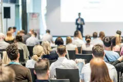 Eine Person hält auf einer Veranstaltung einen Vortrag vor Publikum