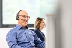 Ein Mitarbeiter des technischen Kundenservice mit Headset im Gespräch